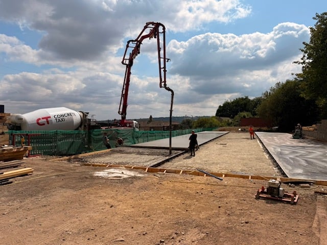 Concrete pump truck with long articulated boom at construction site on dirt ground