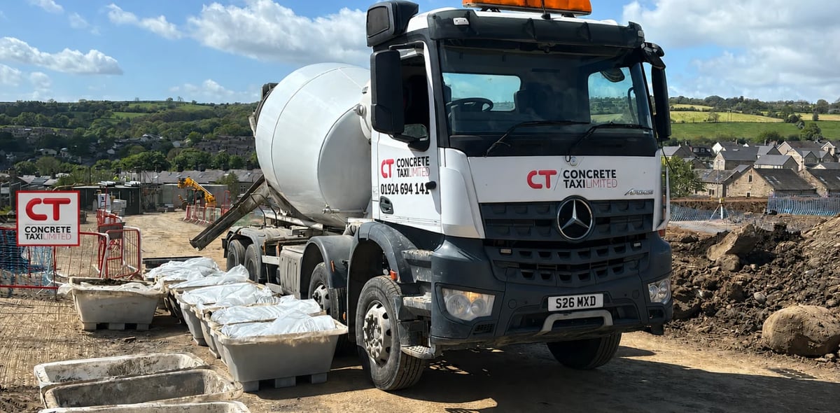 White Mercedes concrete mixer truck at construction site with countryside landscape in background